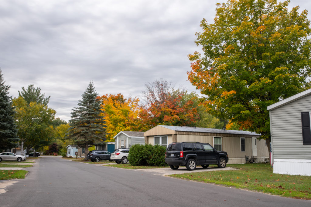 Aspire Website Photography-29 A quiet residential street lined with manufactured homes and cars, showcasing trees with autumn foliage.