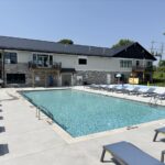 Modern poolside area with lounge chairs adjacent to a mobile homes community on a clear day.