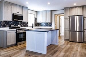 Modern kitchen in Hidden Glades with light wood cabinets, stainless steel appliances, black marble backsplash, center island, and light wood flooring.