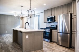 Modern Hidden Glades kitchen with light wood cabinets, stainless steel appliances, center island with sink, two pendant lights, and wood-look flooring.